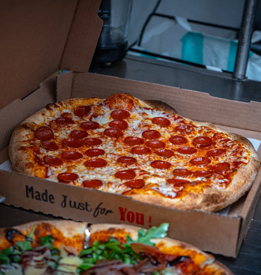 Fresh pepperoni pizza in a Calabria takeout box that reads Made Just for You